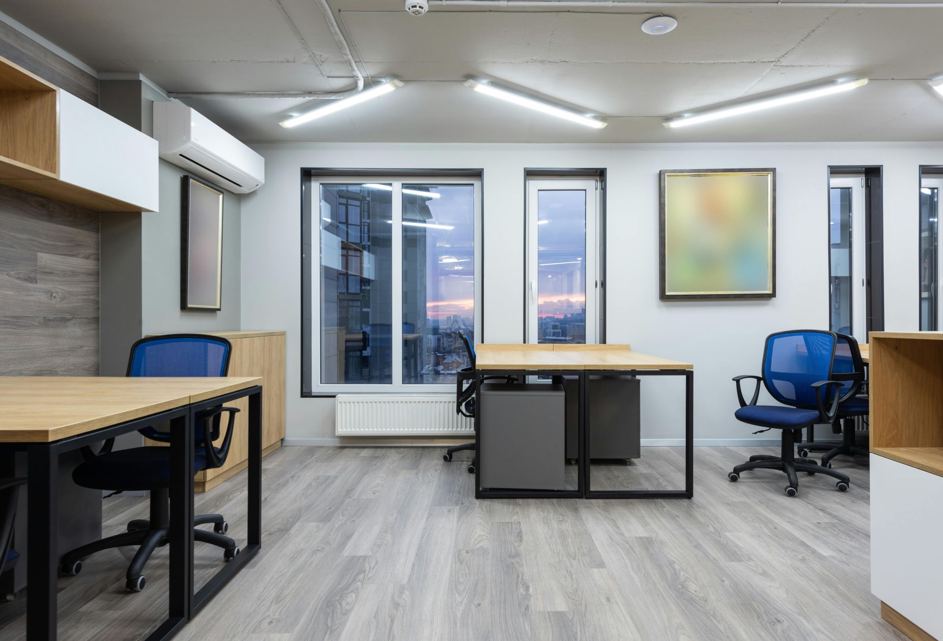 Interior of cotemporary office with wooden tables and chairs illuminated by ceiling lamps